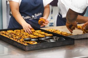 Workers flipping fresh custard tarts out of the tins at Pastéis de Belém