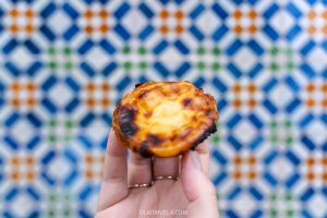 Pastel de nata from Pasteís de Belém in front of a tiled wall